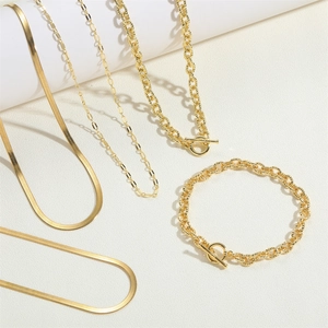 Flat lay of 14K gold plated water wave and paperclip chain necklaces with OT buckle