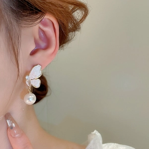 Close-up of elegant butterfly earrings with pearl drops and cubic zirconia on a model
