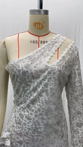 Détail d'une robe de soirée asymétrique à paillettes léopard argentées et dentelle