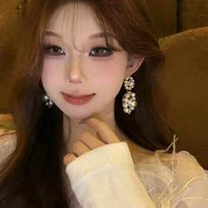 Elegant white pearl drop earrings with gold metal accents on a stylish model