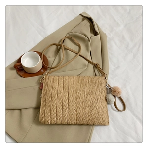Detail of straw woven crossbody bag with colorful pom-pom tassel on a blazer