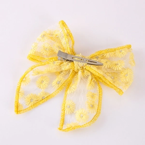 Detail view of yellow embroidered daisy bow hair clip with silver metal alligator grip