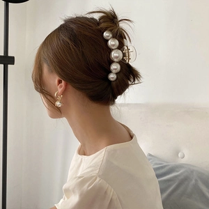 Close-up of elegant large pearl hair claw clip and matching pearl earrings on a model