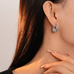 Detailed view of silver twist hoop earring with woven texture worn by a model
