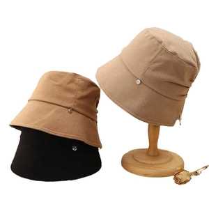 Elegant bucket hats in camel, brown, and black with metal logo detail and sun protection