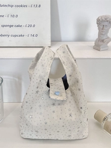 Sac à main beige chic avec étoiles pailletées argentées et bouton cœur bleu sur socle