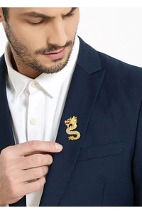 Détail d'une broche dragon dorée avec cristaux et œil rouge sur le revers d'un blazer