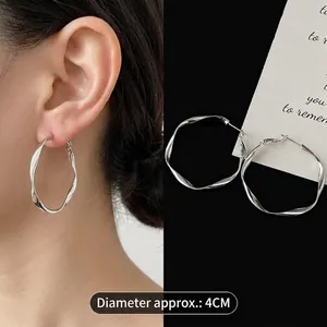 Detail shot of 4cm silver twist C-shaped hoop earrings on model and black background