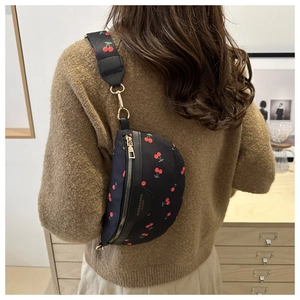 Detailed view of the black cherry print crossbody bag worn over a beige knit sweater