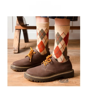Detailed close-up of argyle knit wool socks with classic rib cuffs and vintage leather shoes