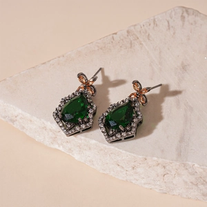 Vintage emerald and amber waterdrop earrings on a stone base in high-end photography