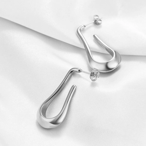 Minimalist silver irregular U-shaped stainless steel drop earrings on white satin