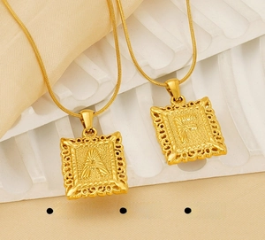 Detail of square embossed gold letter pendant necklaces on polished snake chain