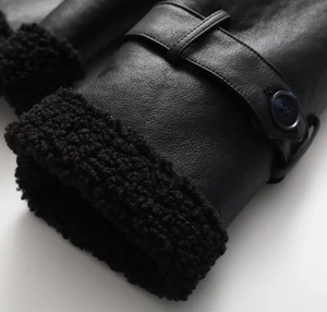 Detail of black faux leather sleeve cuff with shearling lining and adjustable button strap