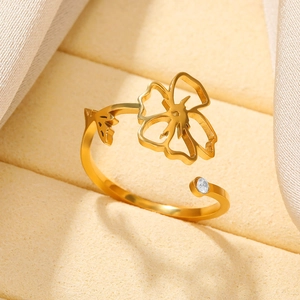 Detail of adjustable gold ring with hollow flower design and sparkling zircon stone
