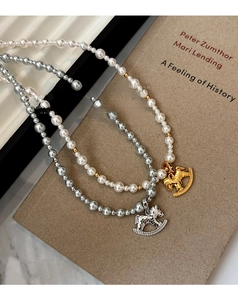 Detailed close-up of vintage rocking horse pendants with pearls and zircon inlays