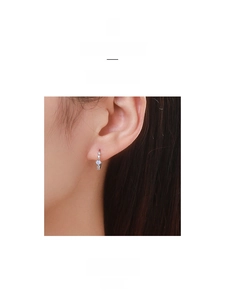 Close-up of S925 silver hoop earring with blue gemstone and diamonds on a model