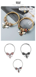Macro detail of stainless steel braided bangle with zircon bee charm and colorful beads