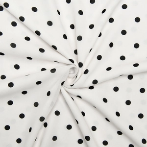 Detail of soft white chiffon fabric with black polka dots showing smooth texture and drape