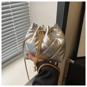 Detail of silver quilted bucket bag with golden chain strap and pearl drawstring accents