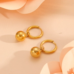 Detail of gold-plated stainless steel hoop earrings featuring dangling bead pendants