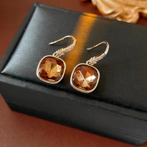 Détail de boucles d'oreilles élégantes en zircon carré marron sur un coffret noir
