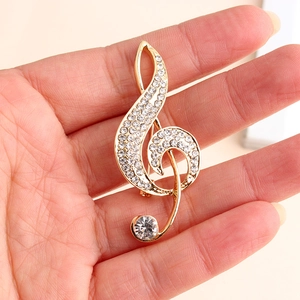 Close-up of golden treble clef brooch with sparkling rhinestones and music note design