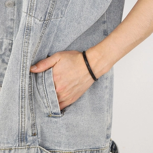 Detail of a men's black C-shaped titanium steel bracelet with a faceted rhombic design
