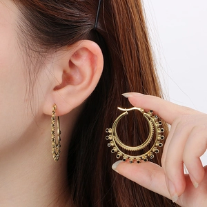Detail of vintage gold double-layer hoop earrings with black beads on a model