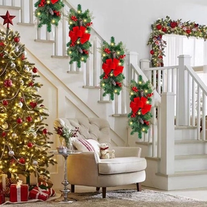 Three Christmas garlands with red bows and LED lights on a staircase railing