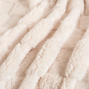 Close-up of thick cream checkered plush blanket featuring soft lamb wool texture