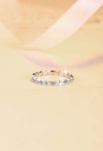 Macro shot of silver ring with marquise-set white zircons on soft warm background