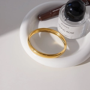 Bracelet jonc en acier inoxydable plaqué or 18 carats sur un plateau en céramique blanc