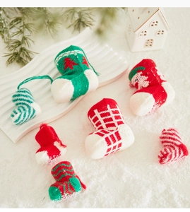Detailed close-up of festive mini knitted Christmas stocking ornaments on snow background