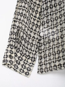 Detail of chiffon shirt cuff with black geometric print and gold stripes on off-white fabric