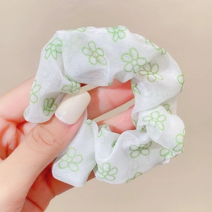 Detail shot of a white mesh scrunchie featuring elegant green floral patterns
