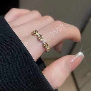 Dettaglio di un anello a catena d'ancora placcato oro 18k con zirconi su un dito femminile