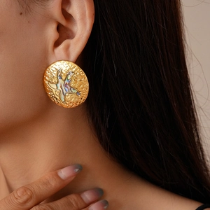 Close-up of golden stainless steel seashell earring with abalone star inlay on ear