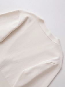 Detailed close-up of white knitted cardigan showing fine ribbed texture and V-neckline