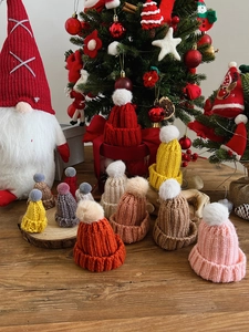 Close-up of mini knitted Christmas hats with white pom-poms in various festive colors