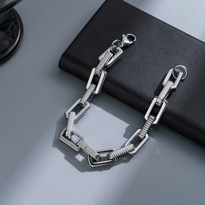 Macro shot of silver stainless steel chain bracelet with lobster clasp on black leather