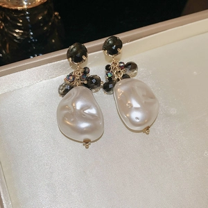 Detailed close-up of bow earrings with baroque pearl drop and dark grey crystal studs