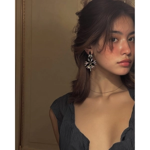 Gros plan de boucles d'oreilles géométriques avec cristaux noirs et transparents en gouttes