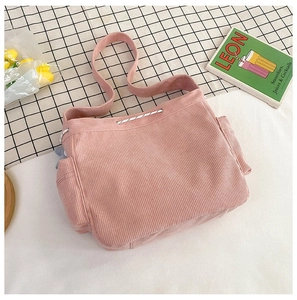 Detail van roze corduroy tote bag met zijzakken en trekkoordsluiting in een lifestyle setting