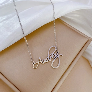 Macro shot of silver titanium steel necklace featuring the custom name Audrey pendant