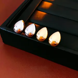 Orecchini a goccia lucidati in oro e argento su un supporto per gioielli nero