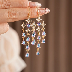 Detail of gold cross earrings with blue purple gradient crystal water drop tassels
