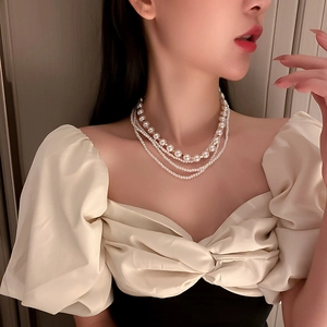 Detail of multi-layer white pearl necklace layered with tiny beads and golden accents