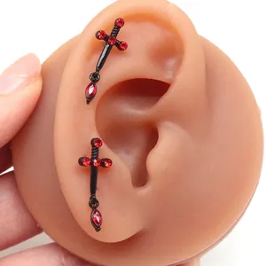 Gothic black dagger earrings with red crystals displayed on a silicone ear model