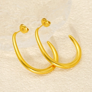 Macro detail of minimalist gold-plated C-shaped earrings with a thick gradient design